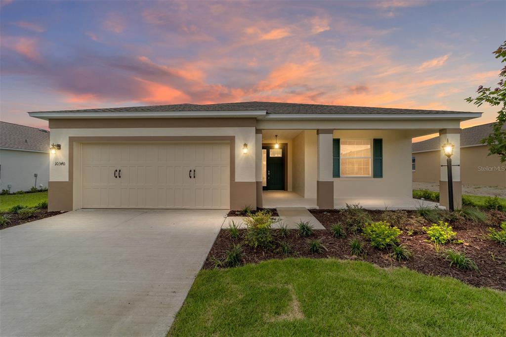 A single-story house with a two-car garage and a covered front porch at sunset — 10340 SW 105TH TERRACE, OCALA, FL