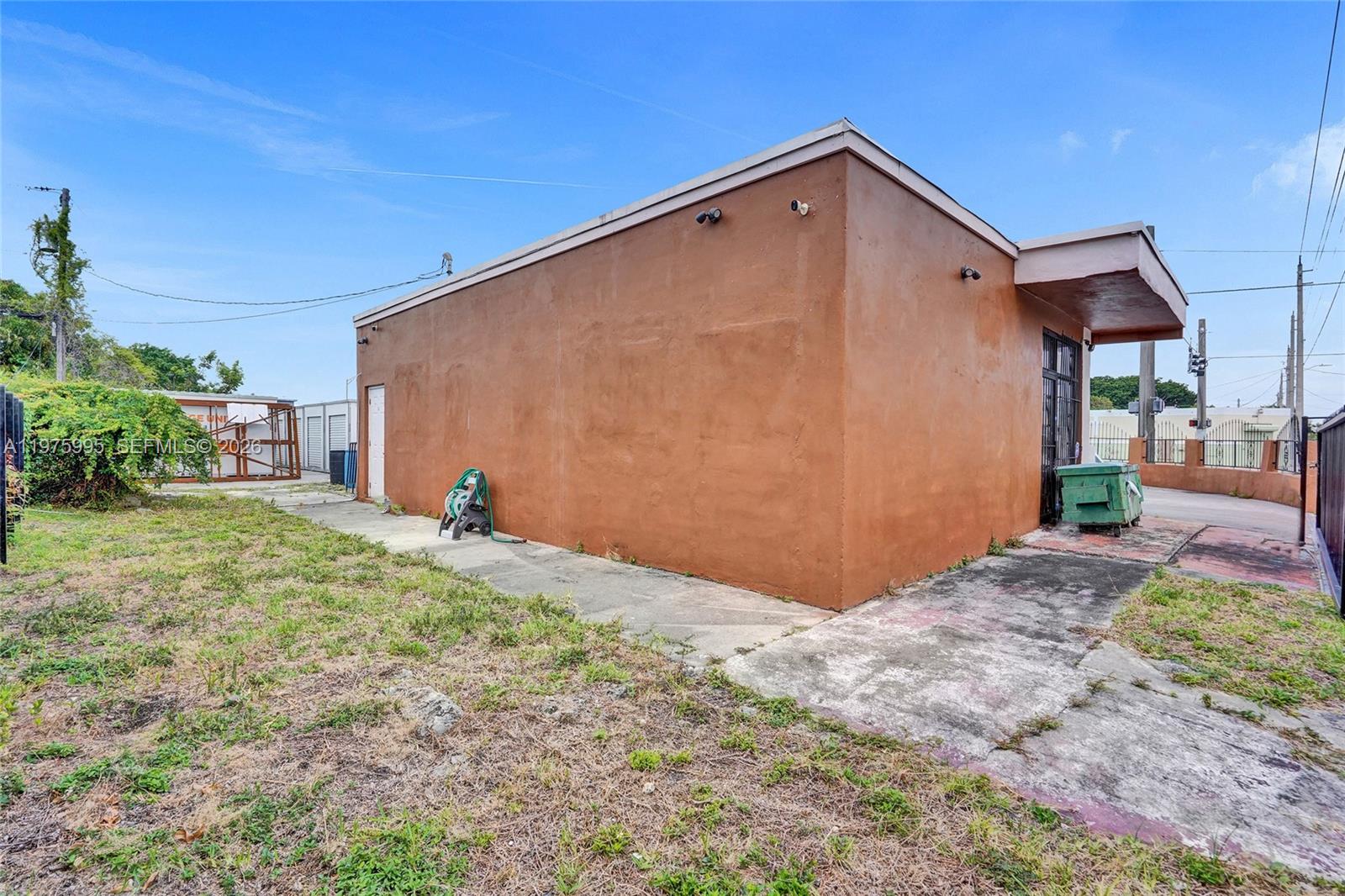 A view of the exterior side of a brown building with a concrete walkway — 5595 NW 17th Ave, Miami FL 33142, MIAMI, FL