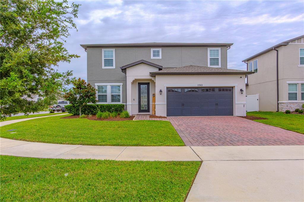 A two-story house features a gray and cream exterior, a brick driveway, and a front lawn — 1261 LONE PALM WAY, ST CLOUD, FL