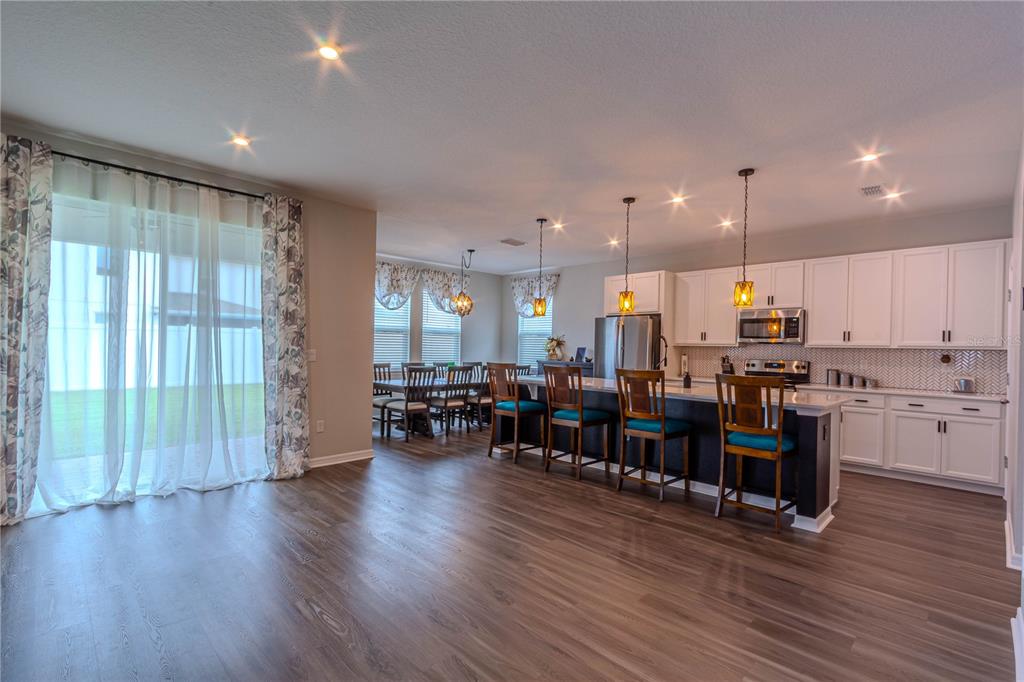 An open-concept kitchen with white cabinets, a dark island, and a dining area — 1261 LONE PALM WAY, ST CLOUD, FL