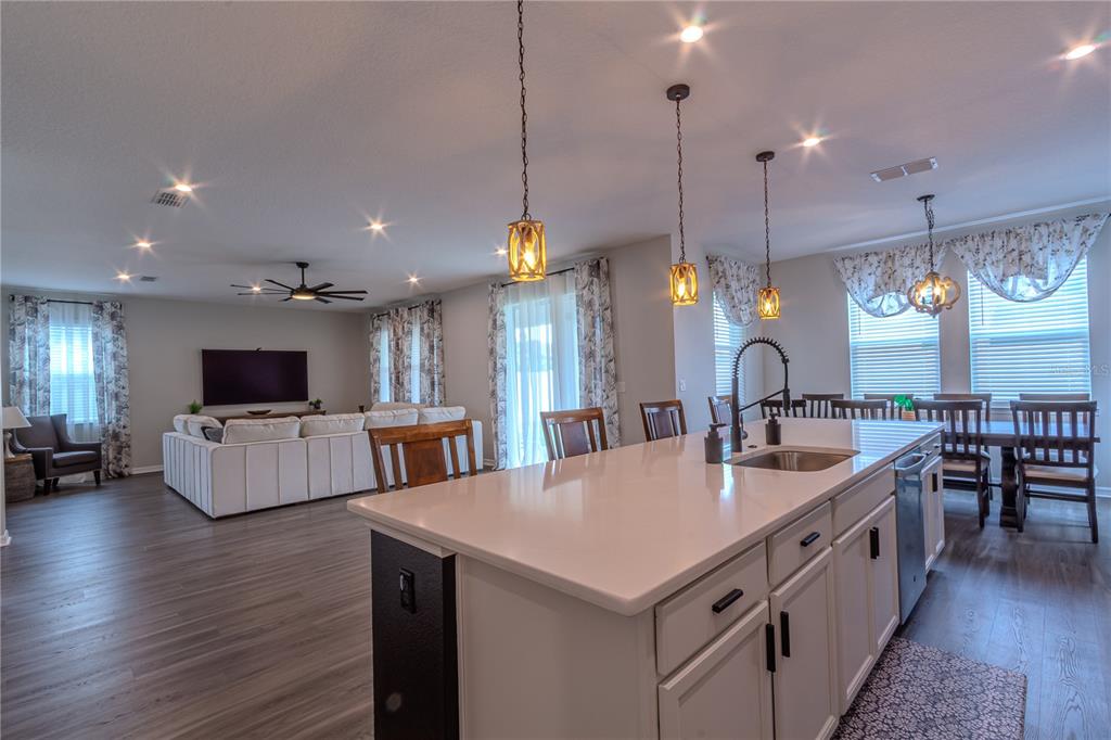 An open-concept kitchen with a large island overlooks a living room with a white sofa — 1261 LONE PALM WAY, ST CLOUD, FL
