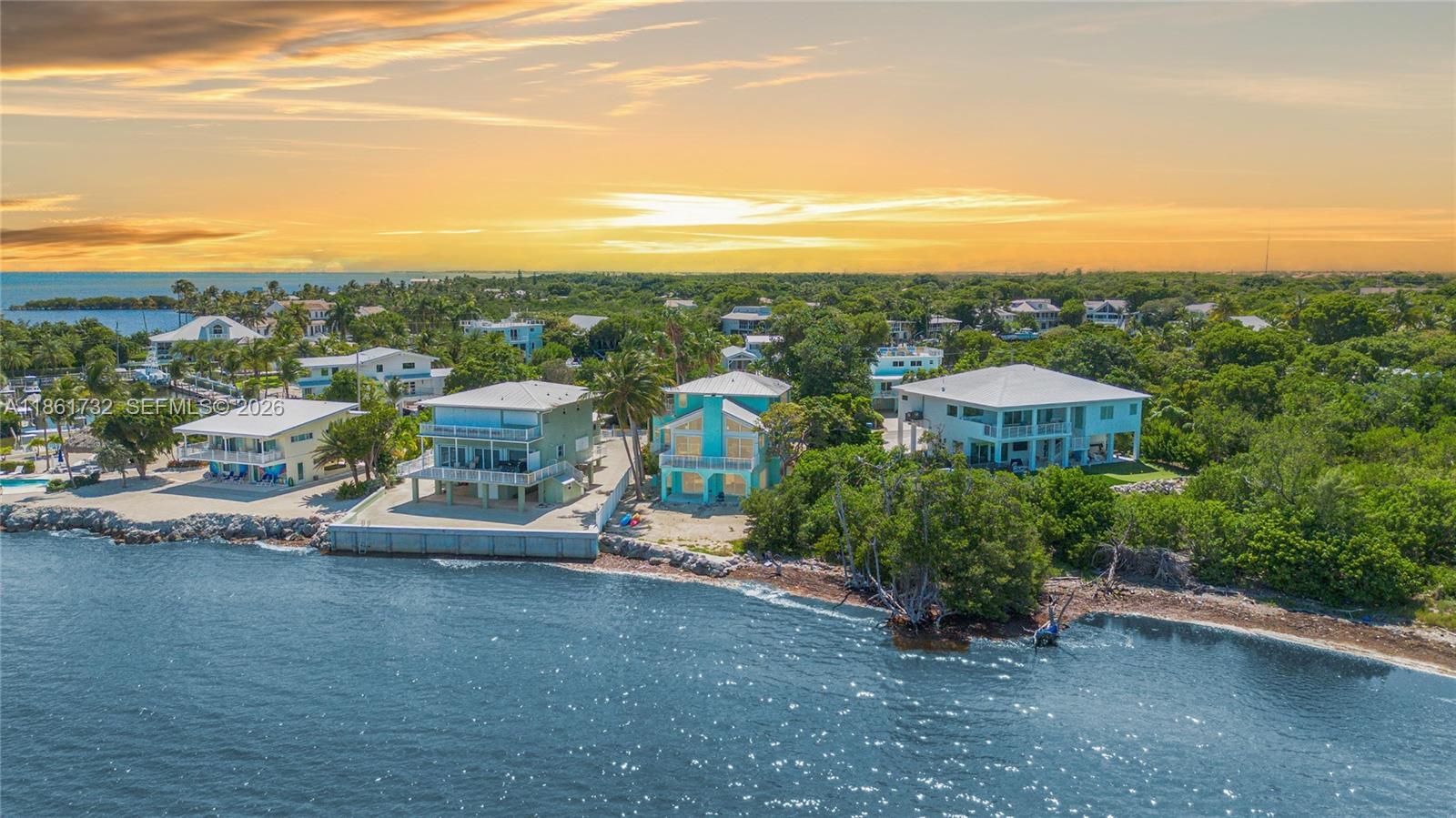 An aerial view shows three waterfront houses along a rocky shoreline at sunset — 316 N Dr, Islamorada FL 33036, ISLAMORADA, FL