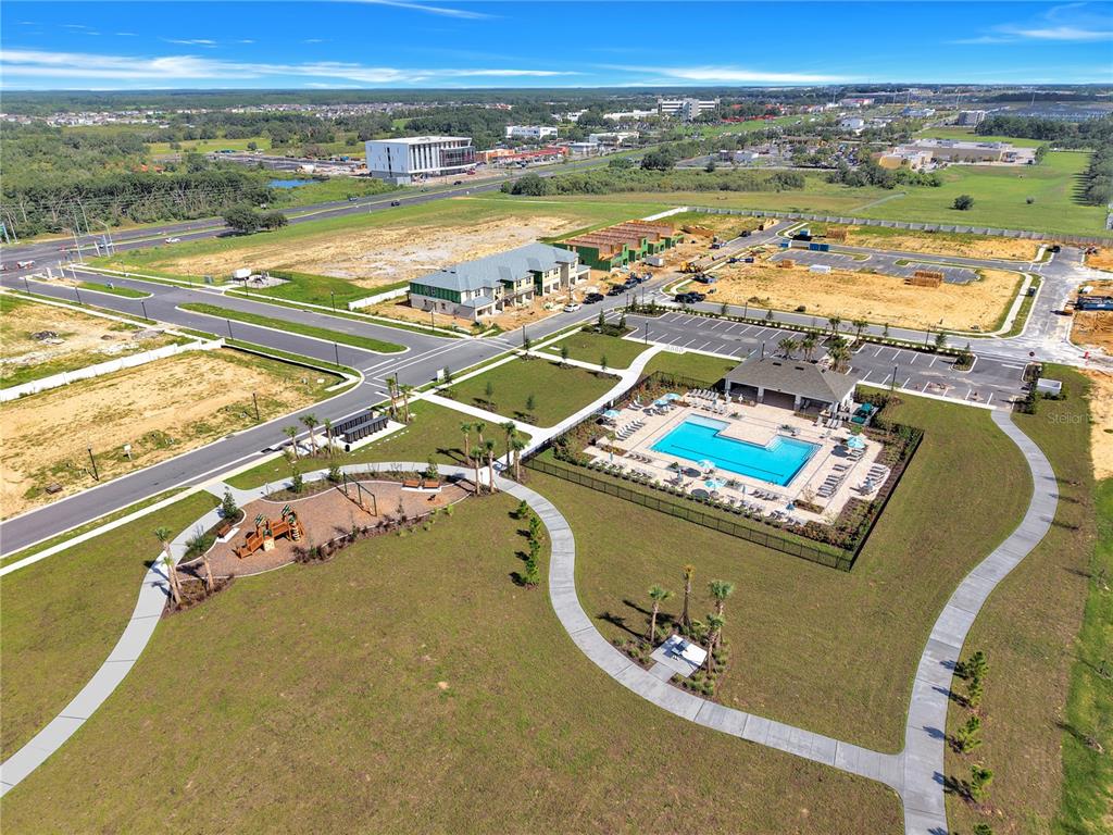 An aerial view shows a community pool, playground, and new construction in a suburban area — 4292 CHESTER SPRINGS BOULEVARD, DAVENPORT, FL