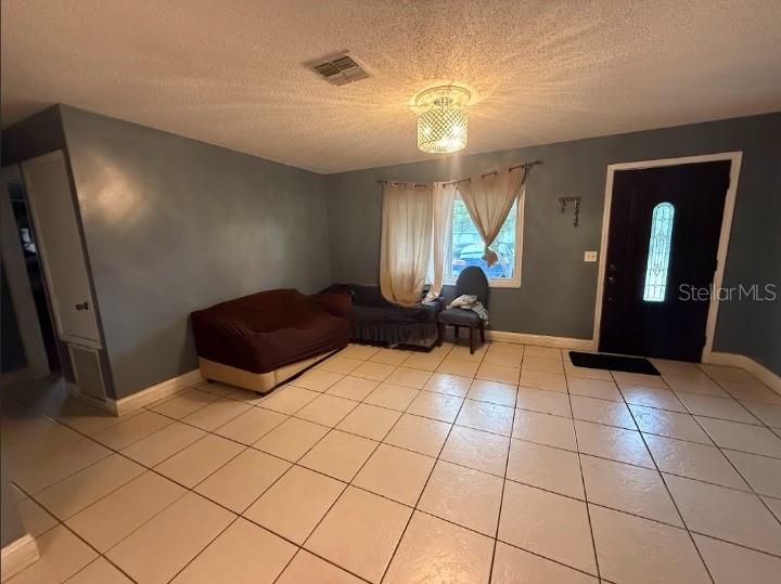A living room with blue walls, tiled floors, a brown sofa, and a front door — 2533 EL PORTAL AVENUE, SANFORD, FL