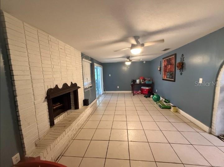 A living room features a white brick fireplace, tile flooring, and blue walls — 2533 EL PORTAL AVENUE, SANFORD, FL