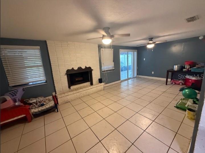 A living room features a white brick fireplace, tile flooring, blue walls, and two ceiling fans — 2533 EL PORTAL AVENUE, SANFORD, FL