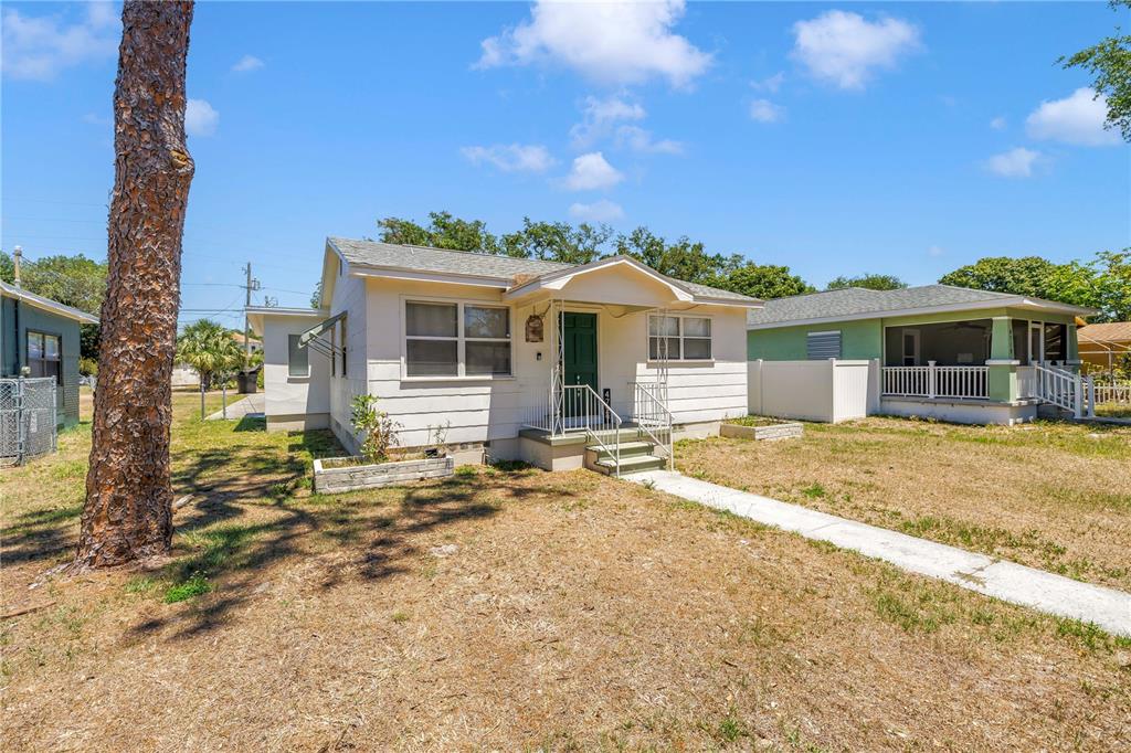 A single-story white house with a green front door and a concrete walkway — 4729 12TH AVENUE S, ST PETERSBURG, FL