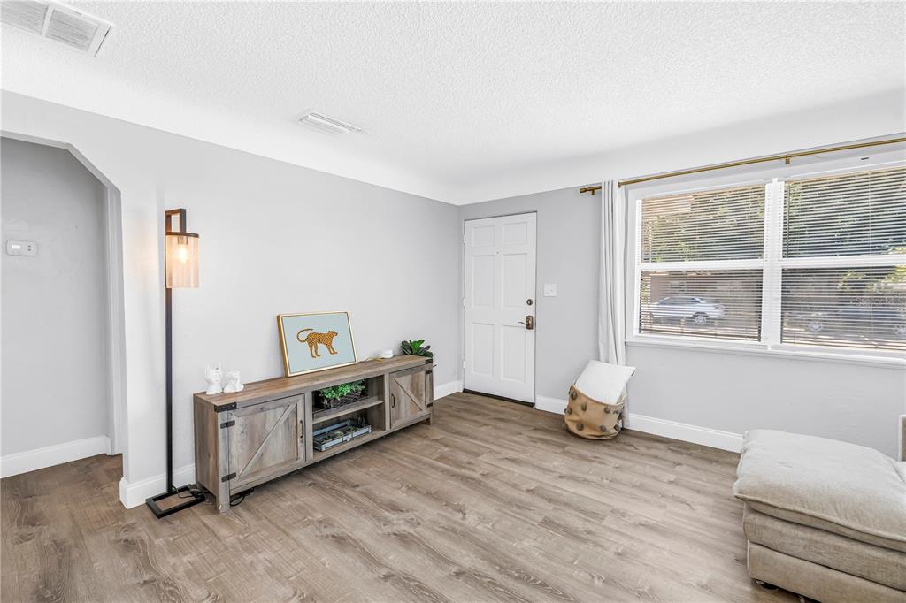 A living room features light gray walls, wood-look flooring, a media console, and a front door — 4729 12TH AVENUE S, ST PETERSBURG, FL