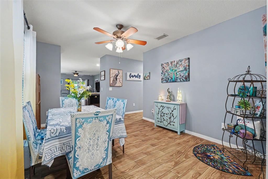 A dining room features a blue patterned tablecloth, matching chairs, wood-look flooring, and peacock-themed decor — 3918 WILLOW HAMMOCK DRIVE, PALMETTO, FL