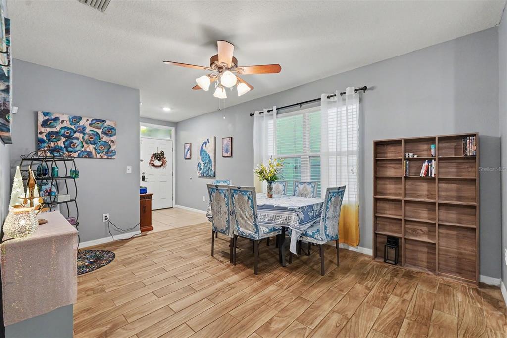 A dining area features wood-look tile flooring, a ceiling fan, and a wooden bookshelf — 3918 WILLOW HAMMOCK DRIVE, PALMETTO, FL