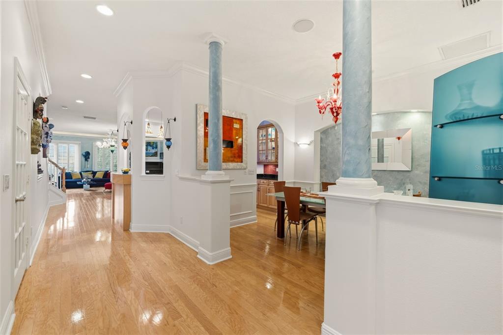A dining area and hallway feature hardwood floors, blue columns, and a red chandelier — 615 SAXONY BOULEVARD, ST PETERSBURG, FL