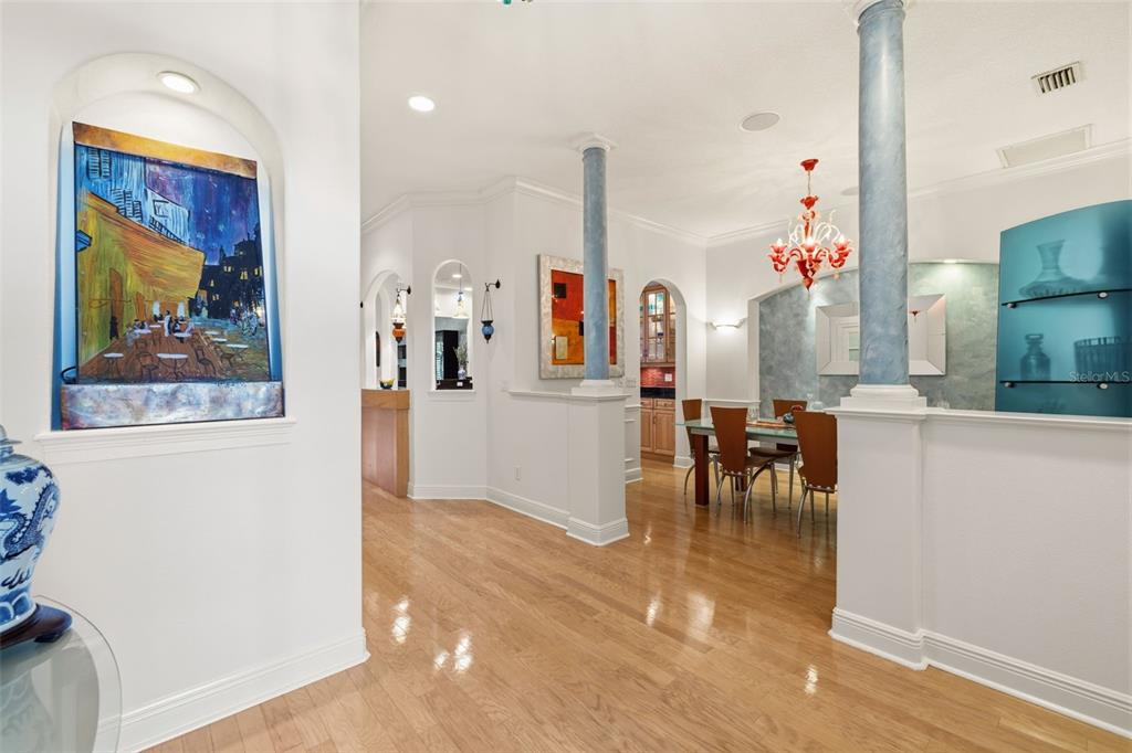 A dining area with a red chandelier is visible beyond a hallway with blue columns — 615 SAXONY BOULEVARD, ST PETERSBURG, FL