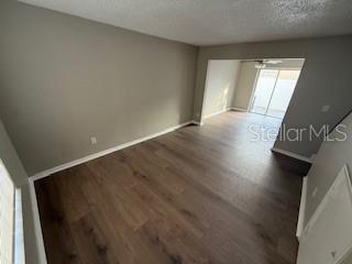 An empty room with wood-look flooring leads to a dining area with a sliding glass door — 3009 S MANHATTAN AVENUE UNIT B, TAMPA, FL
