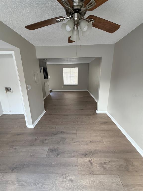 A living area with wood-look flooring, a ceiling fan, and a view into another room — 3009 S MANHATTAN AVENUE UNIT B, TAMPA, FL