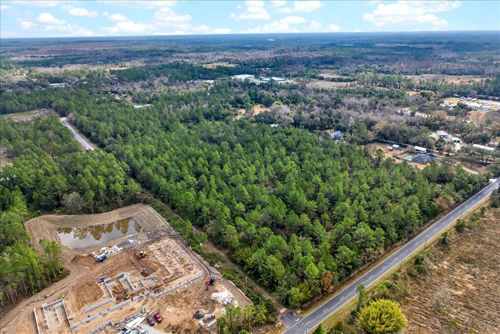 An aerial view shows a construction site with a pond next to a forested area — 0 Old Haw Creek Road, FL 32110, FL