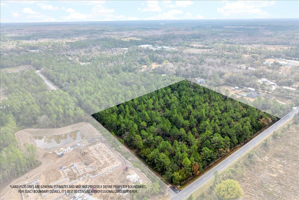 An aerial view shows a rectangular, wooded plot of land adjacent to a paved road — 0 Old Haw Creek Road, FL 32110, FL