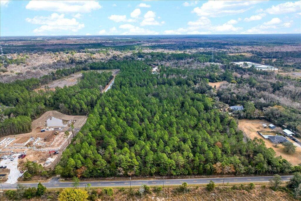 An aerial view shows a wooded lot adjacent to a construction site and a road — 0 Old Haw Creek Road, FL 32110, FL