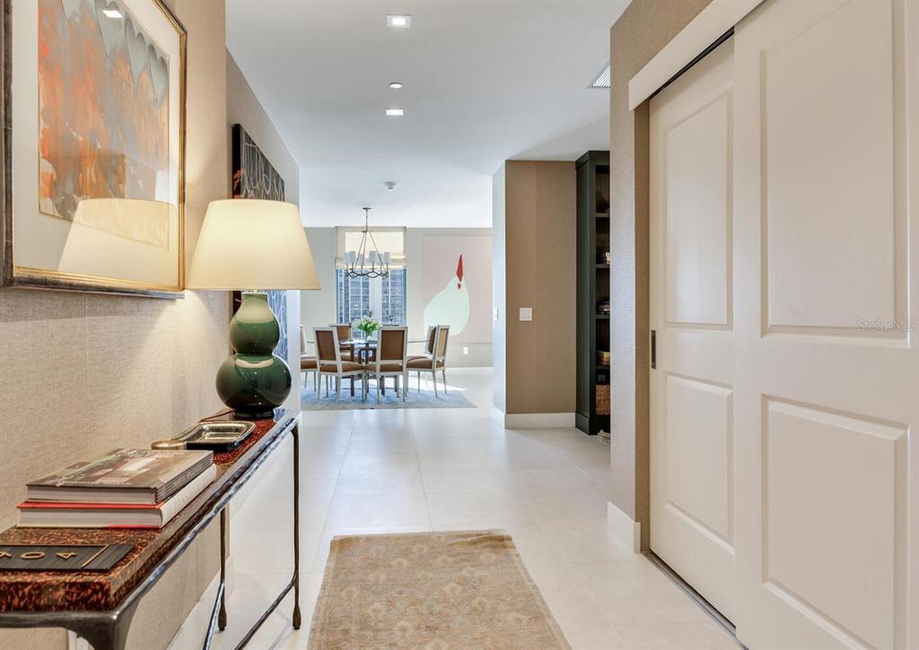 A hallway with a console table and lamp leads to a dining area with chairs — 3015 S YSABELLA AVENUE UNIT 904, TAMPA, FL