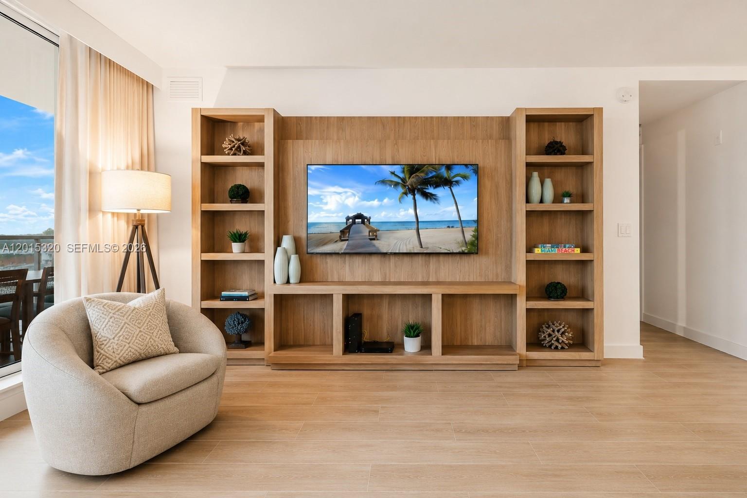 A living room features a light wood media wall with built-in shelving and a television — 2301 Collins Ave # 1129, Miami Beach FL 33139, MIAMI BEACH, FL