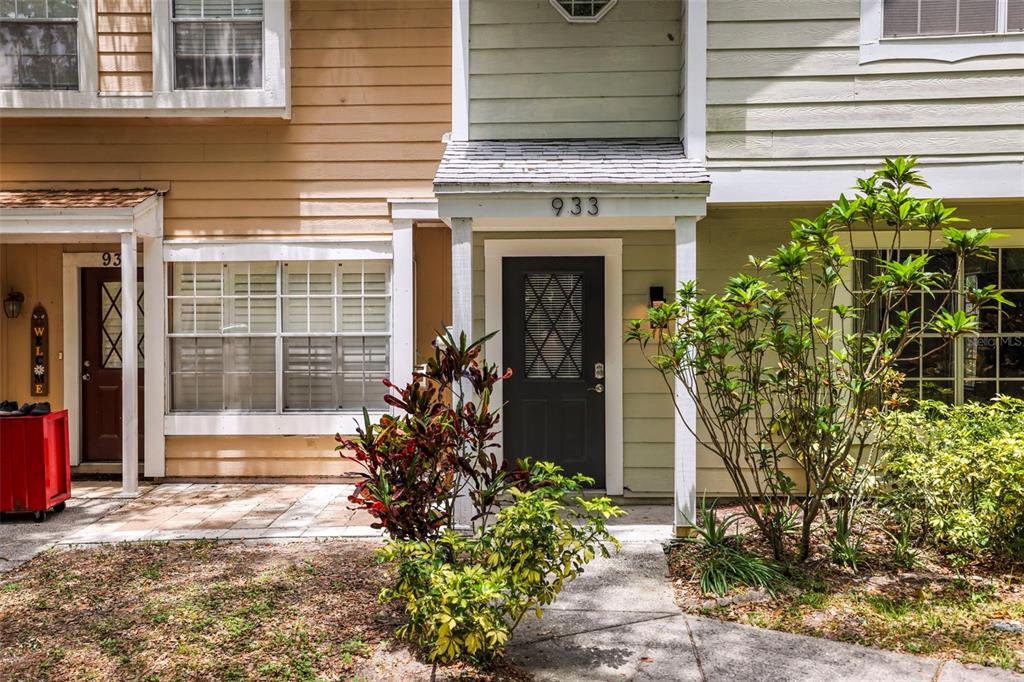 The exterior of two adjacent townhomes features light-colored siding, dark doors, and small front porches — 933 HAMILTON COURT, PALM HARBOR, FL