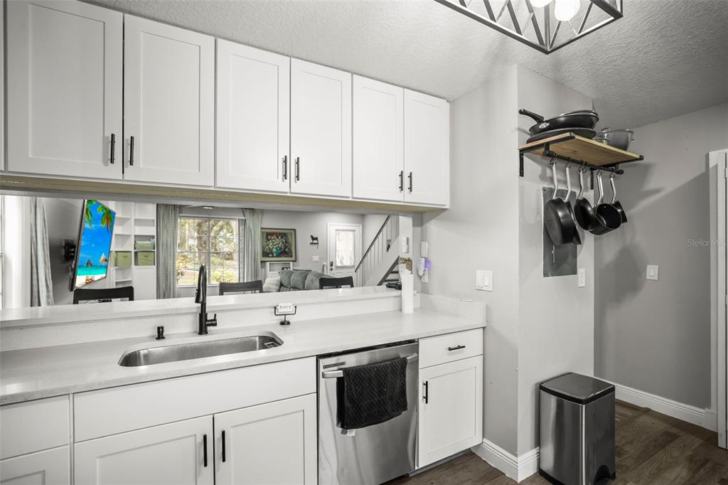 A kitchen features white cabinets, a stainless steel dishwasher, and a mirrored backsplash — 933 HAMILTON COURT, PALM HARBOR, FL