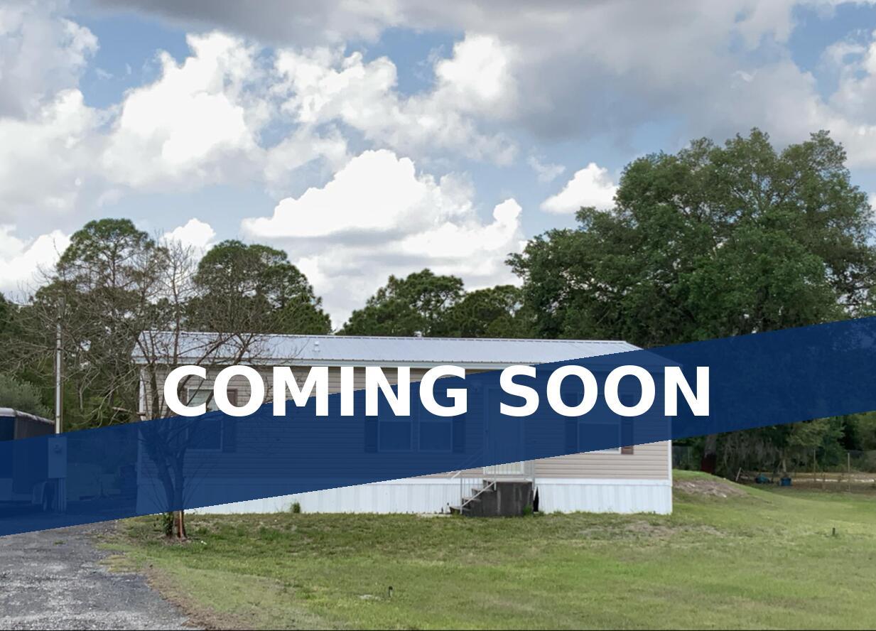 A white storm door leads to a small porch on the side of a house — 220 N Sendero Street, Clewiston FL 33440, CLEWISTON, FL