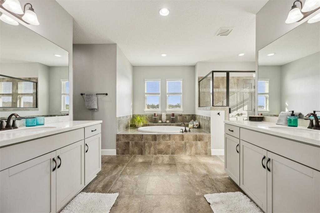 A primary bathroom features dual vanities, a tiled soaking tub, and a glass-enclosed shower — 85030 Majestic Walk Boulevard, FL 32034, FL