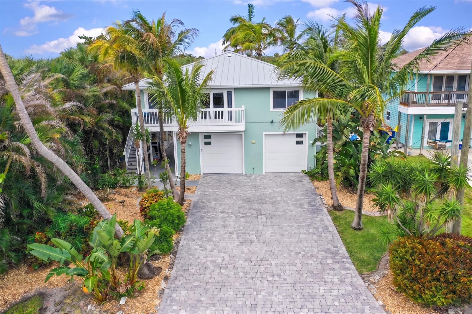 A two-story light green house with a paved driveway and palm trees in the front — 413 Hernando Street, Fort Pierce FL 34949, FORT PIERCE, FL