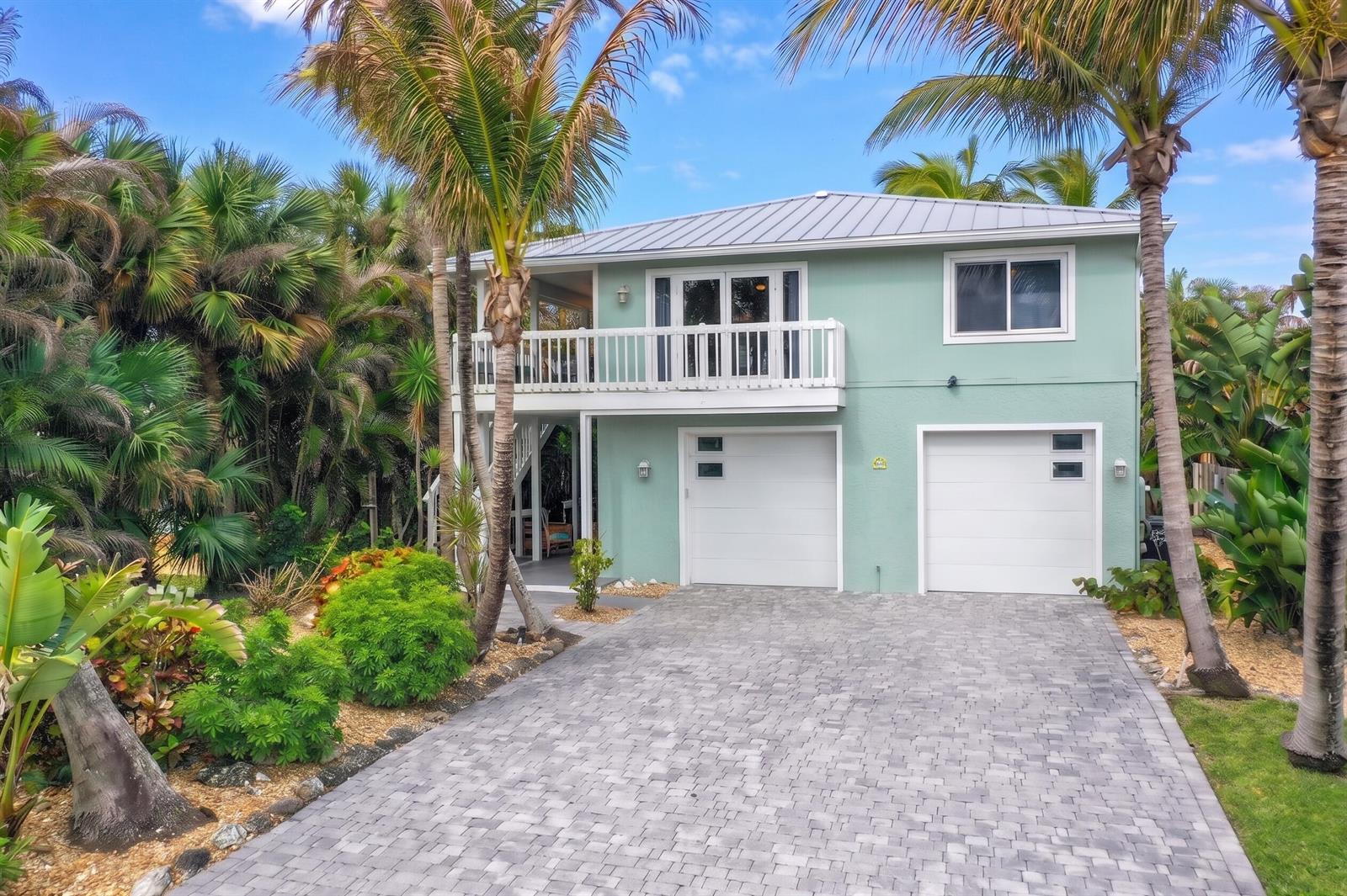 A two-story light green house with a metal roof, two garage doors, and a balcony — 413 Hernando Street, Fort Pierce FL 34949, FORT PIERCE, FL