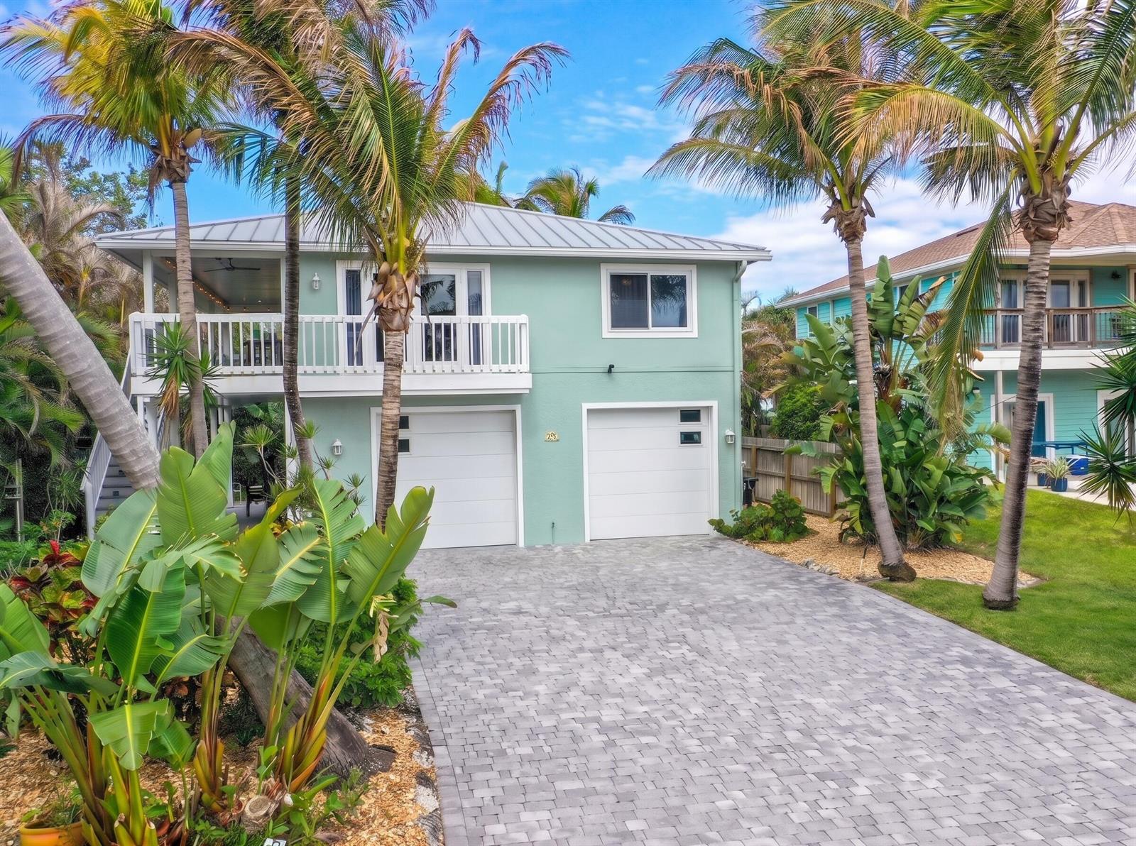 A two-story light green house with a paved driveway, two garage doors, and palm trees — 413 Hernando Street, Fort Pierce FL 34949, FORT PIERCE, FL