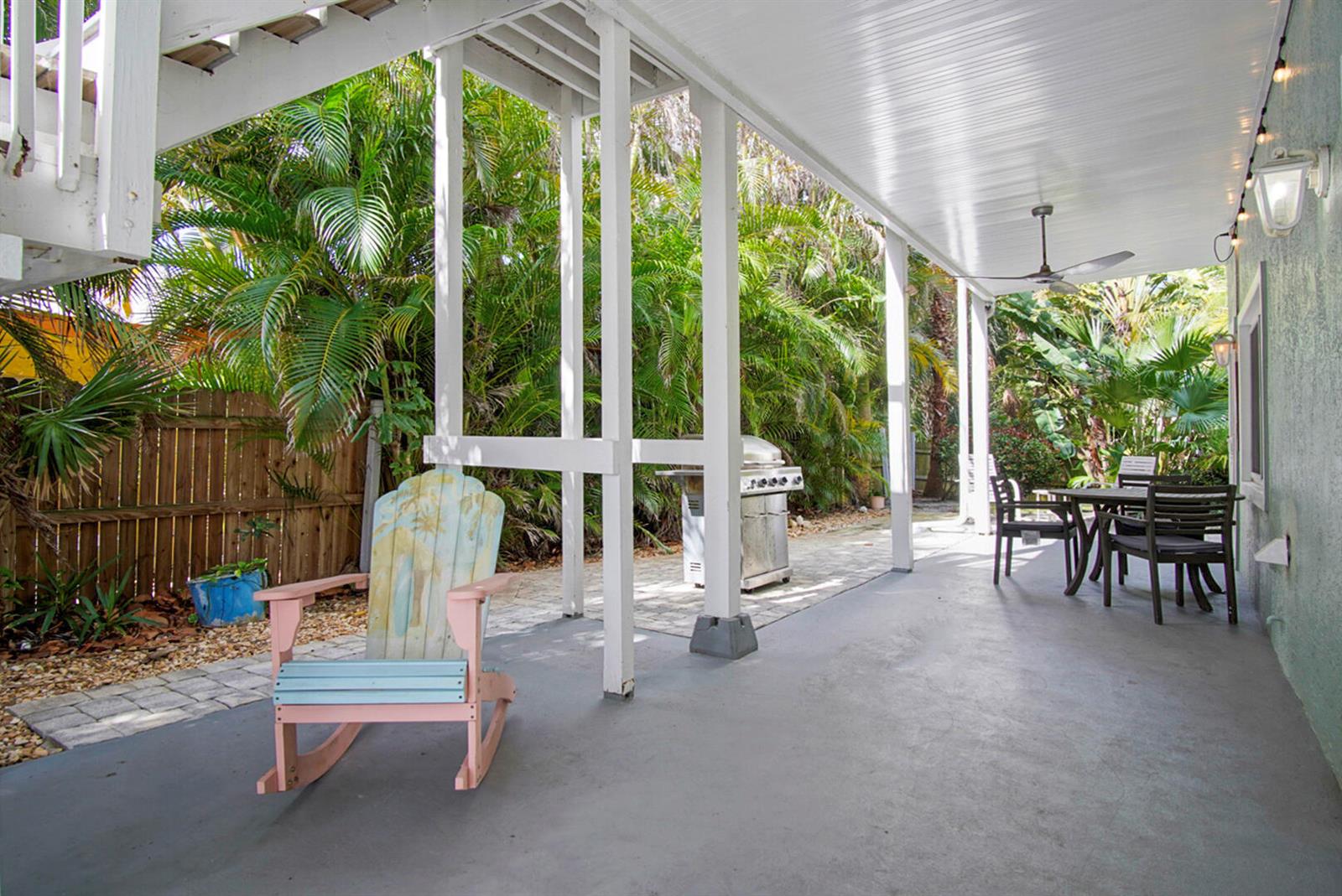 A covered patio features a painted rocking chair, a grill, and outdoor dining furniture — 413 Hernando Street, Fort Pierce FL 34949, FORT PIERCE, FL