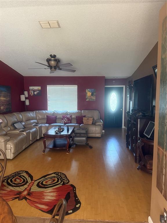 A living room features a beige sectional sofa, a coffee table, and a butterfly-shaped rug — 2507 MARTHA LANE, LAND O LAKES, FL