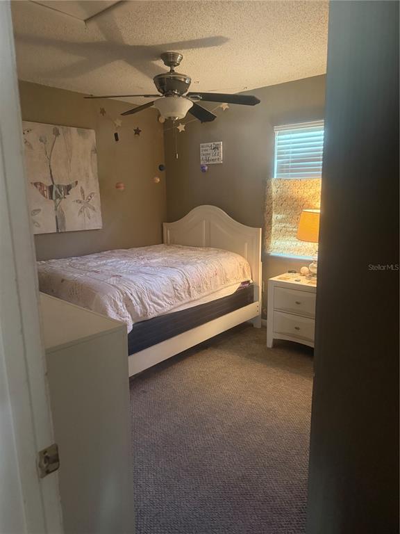 A bedroom features a white bed frame, a ceiling fan, and a bedside table — 2507 MARTHA LANE, LAND O LAKES, FL