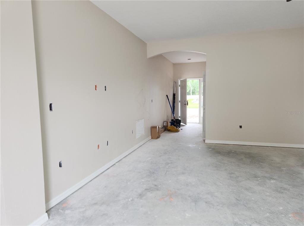 An unfinished room with beige walls, concrete flooring, and an open doorway leading outside — 411 SHANNON ESTATES COURT, PLANT CITY, FL