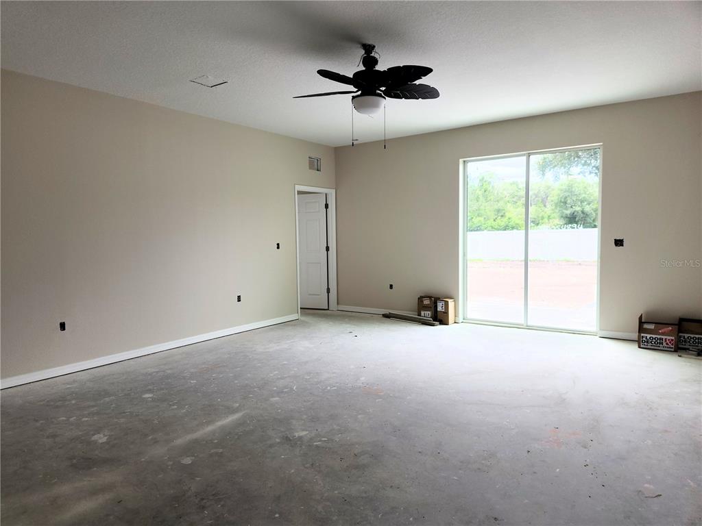 An unfinished room with concrete flooring, a ceiling fan, and a sliding glass door — 411 SHANNON ESTATES COURT, PLANT CITY, FL