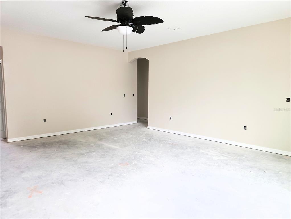 An empty room with beige walls, a ceiling fan, and an unfinished concrete floor — 411 SHANNON ESTATES COURT, PLANT CITY, FL