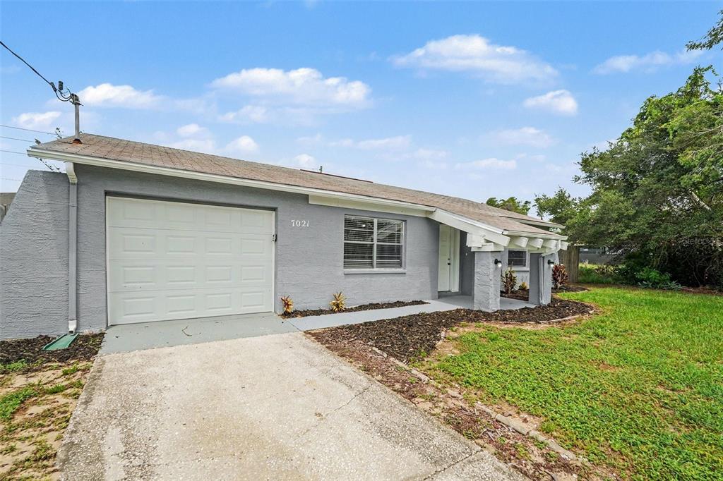 A gray single-story house with a white garage door and a concrete driveway — 7021 LANDOVER BOULEVARD, SPRING HILL, FL