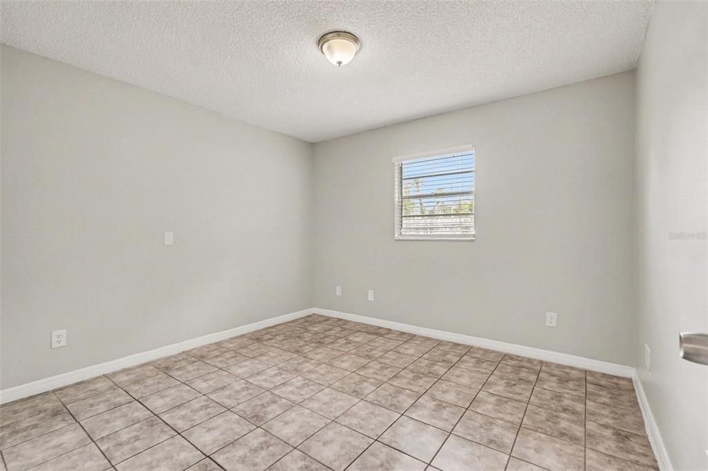 An empty bedroom with light gray walls, a tiled floor, and a single window — 7021 LANDOVER BOULEVARD, SPRING HILL, FL