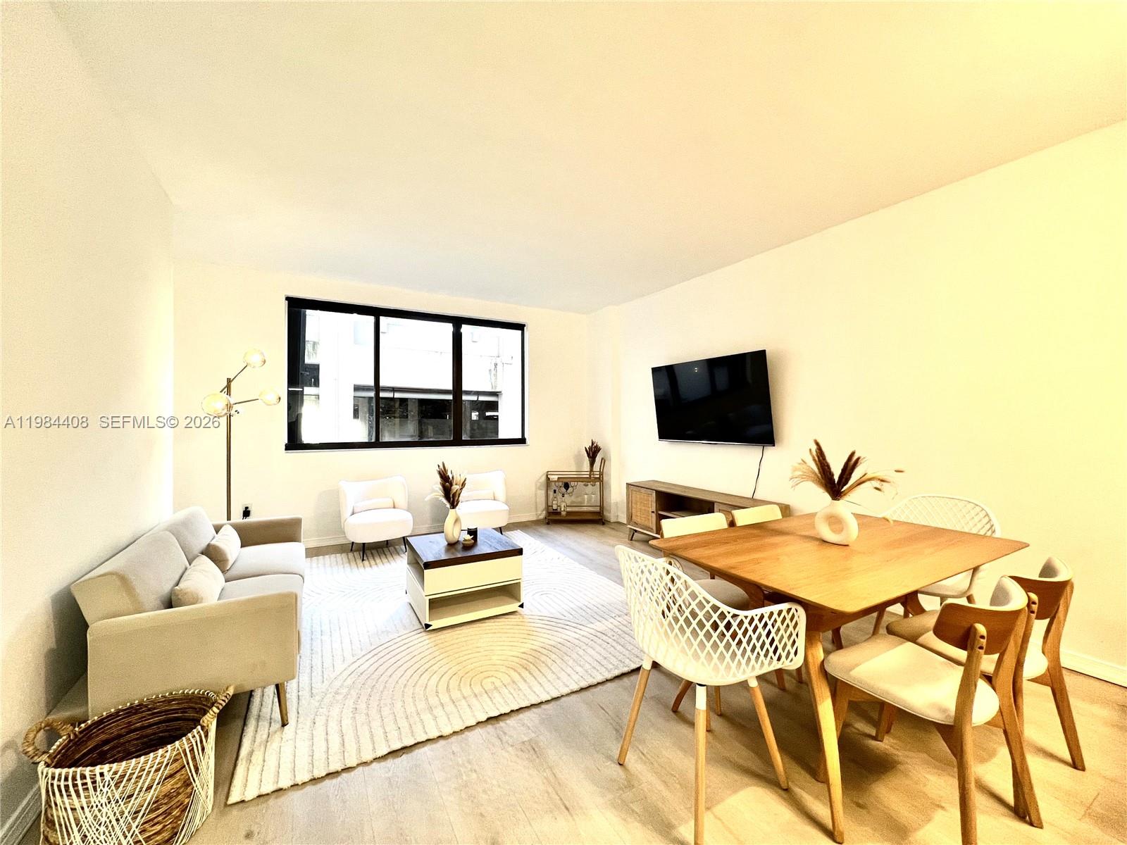 A living and dining area features light wood flooring, a large area rug, and modern furniture — 540 Brickell Key Dr # 202, Miami FL 33131, MIAMI, FL