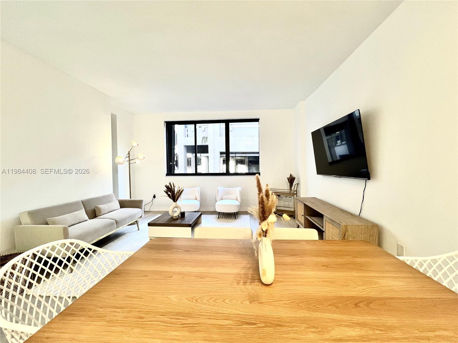 A living and dining area features a sofa, two armchairs, a television, and wood furniture — 540 Brickell Key Dr # 202, Miami FL 33131, MIAMI, FL