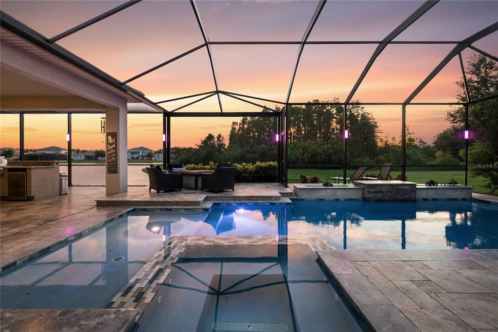 A screened-in patio features a swimming pool, a hot tub, and an outdoor kitchen area — 2611 COCO PALM CIRCLE, WESLEY CHAPEL, FL