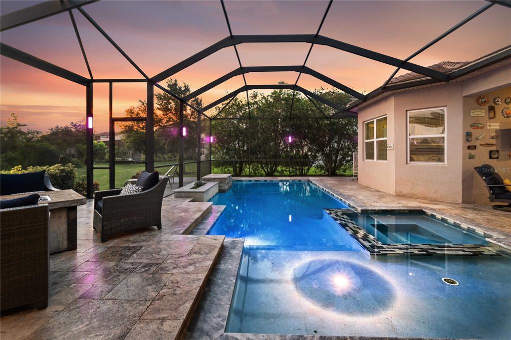 A screened-in patio features a swimming pool, a hot tub, and stone tile flooring — 2611 COCO PALM CIRCLE, WESLEY CHAPEL, FL