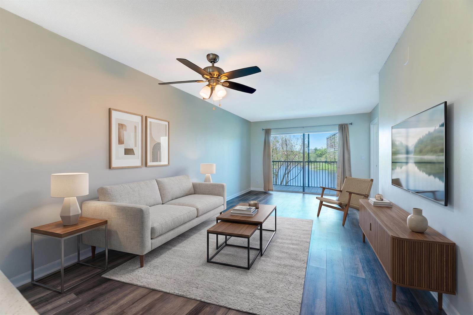 A living room features a sofa, coffee tables, media console, and a balcony overlooking water — 2226 N Cypress Bend Drive # 308, Pompano Beach FL 33069, POMPANO BEACH, FL