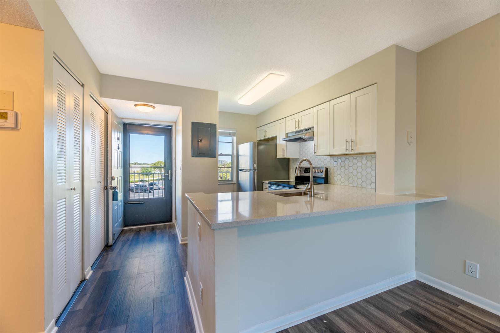 A kitchen with white cabinets, a quartz countertop, and a view of the outdoors — 2226 N Cypress Bend Drive # 308, Pompano Beach FL 33069, POMPANO BEACH, FL