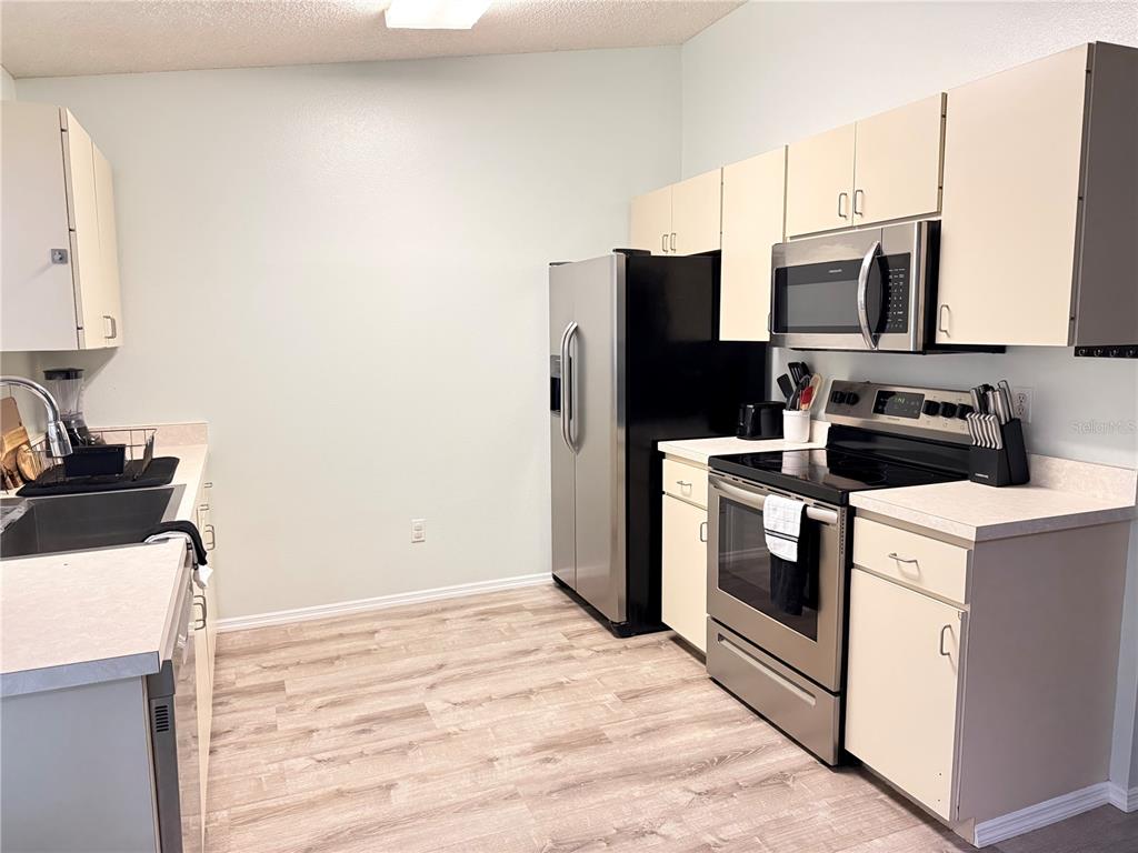 A kitchen features light-colored cabinets, stainless steel appliances, and wood-look flooring — 344 49TH STREET W, PALMETTO, FL