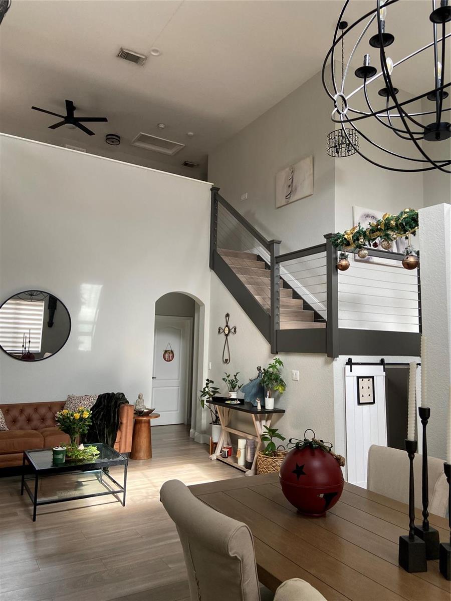 A living and dining area features a staircase with cable railings and a chandelier — 20439 NW 9th Court, Miami FL 33169, MIAMI, FL