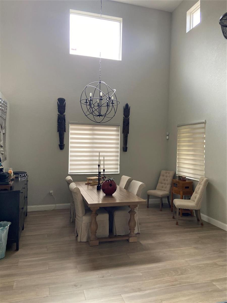 A dining room with high ceilings, a wooden table, and a spherical chandelier — 20439 NW 9th Court, Miami FL 33169, MIAMI, FL