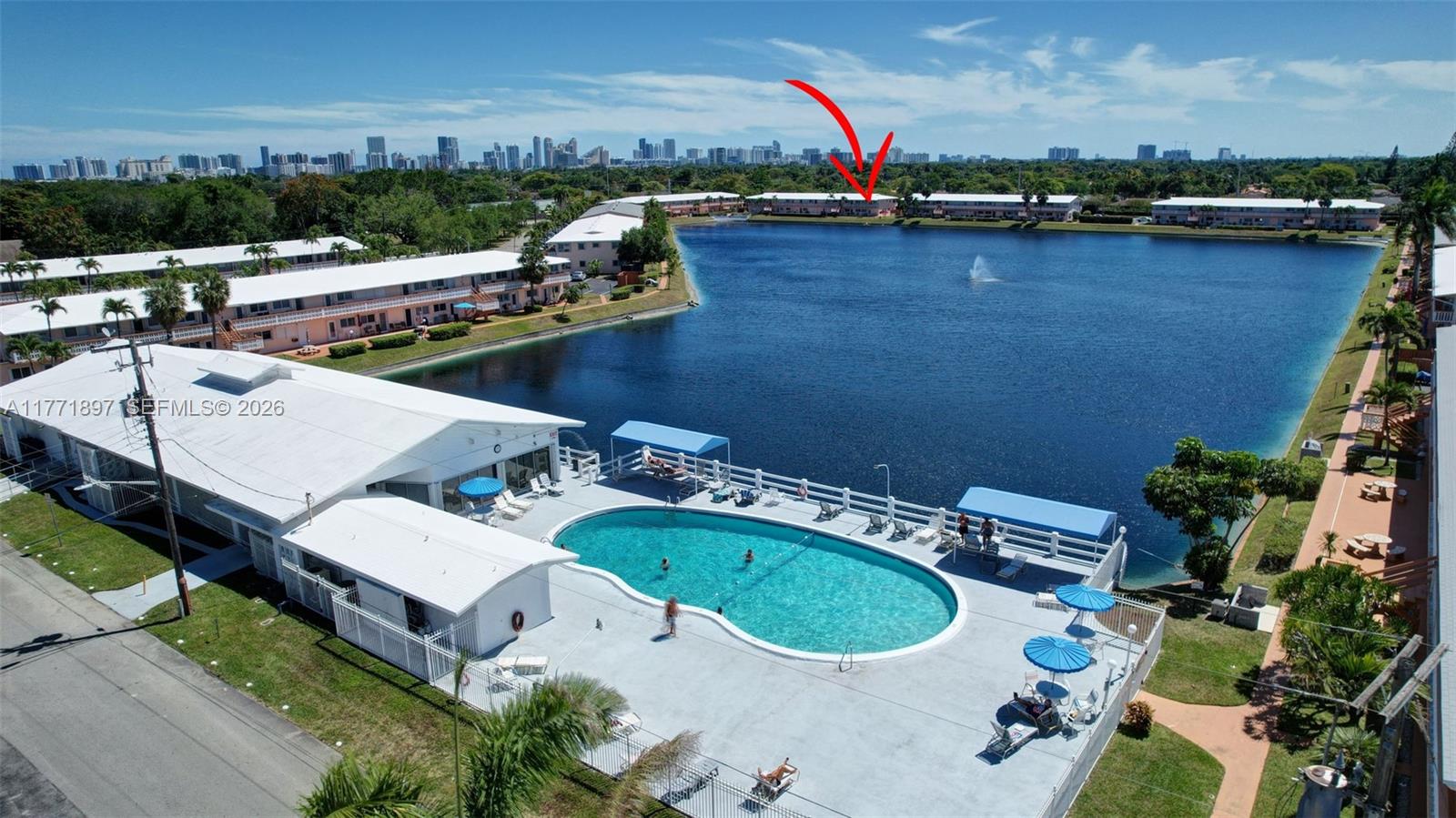 An aerial view shows a swimming pool, a lake, and multiple residential buildings — 1012 SW 11th St # 20N, Hallandale Beach FL 33009, HALLANDALE BEACH, FL