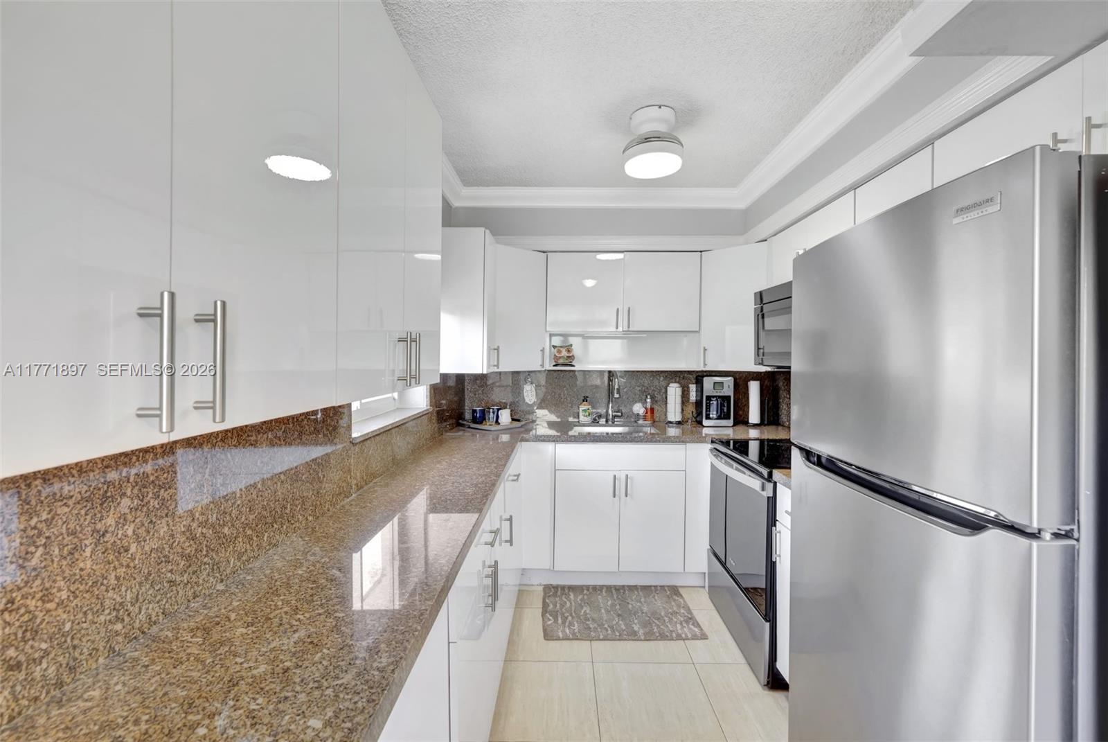 A kitchen features white cabinets, granite countertops, and stainless steel appliances — 1012 SW 11th St # 20N, Hallandale Beach FL 33009, HALLANDALE BEACH, FL