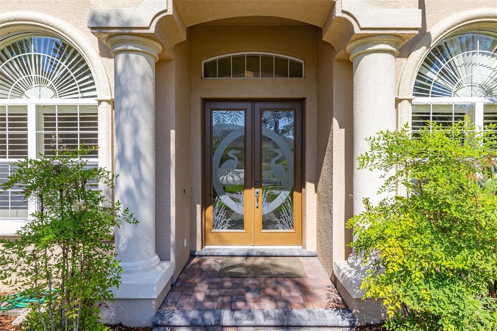The exterior entrance features double glass doors with heron etchings flanked by two white columns — 6535 EAGLE RIDGE WAY, LAKELAND, FL